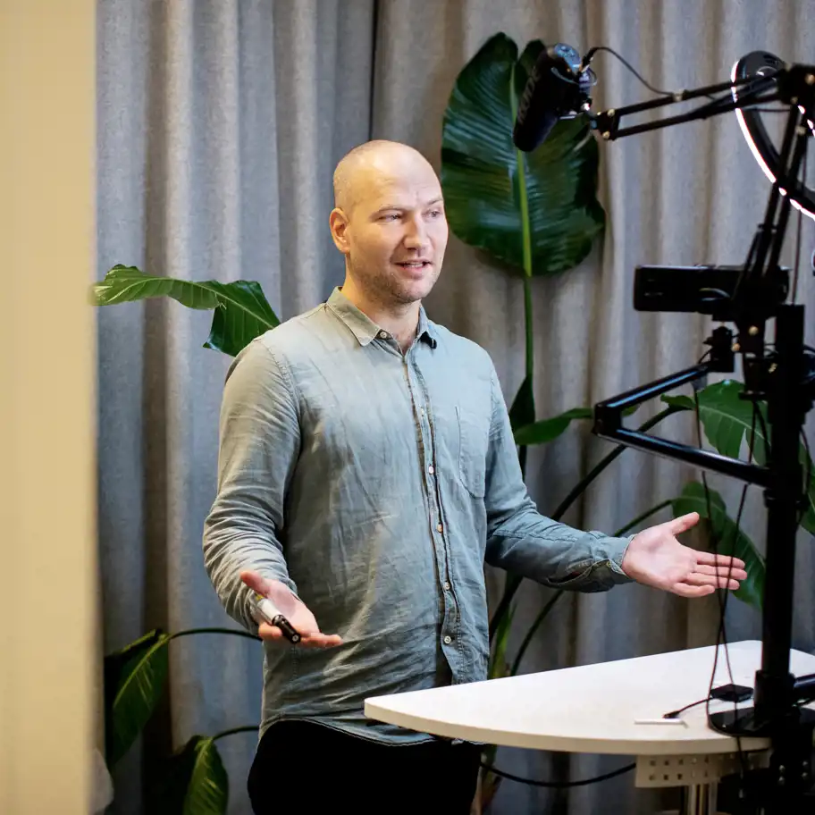 Simon Strandvik står framför en kamera och mikrofon.