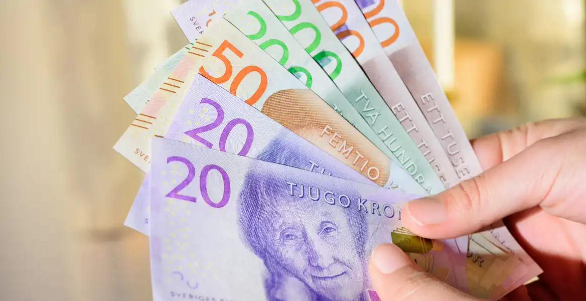 Närbild på en hand som håller i svenska sedlar.