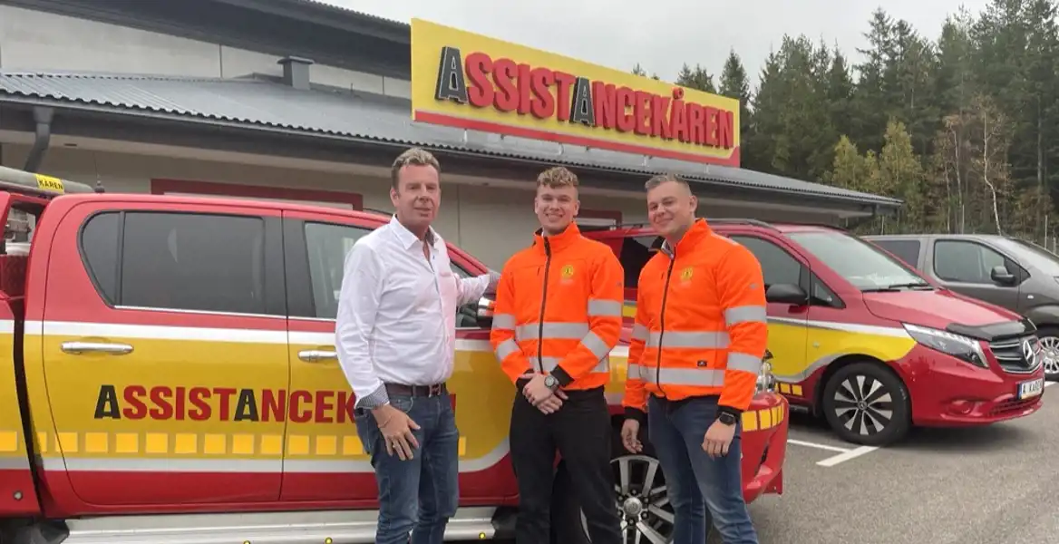 Tre män framför en skylt